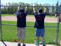 Two players in blue shirts looking through fence